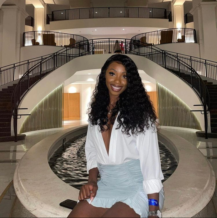 Woman posing in a large, elegant indoor atrium with a staircase.
