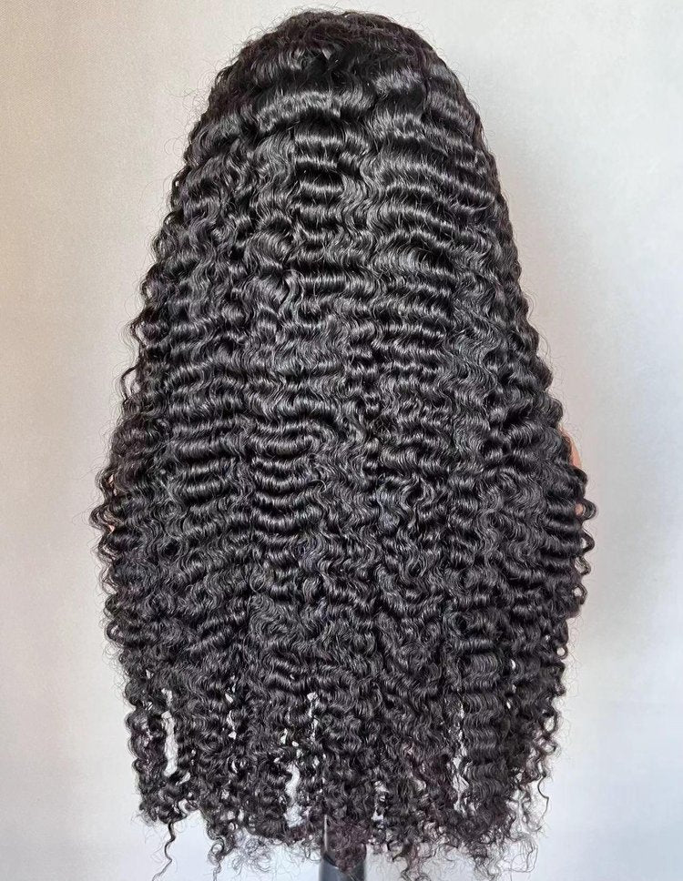 Black curly wig on a mannequin head against a plain background